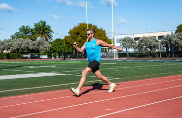 Fototapeta premium Sport runner completing a marathon. Sport training. Man sportsman running for exercise. Man running at racetrack outdoor. Runner sprinted with incredible speed. Outdoor gym