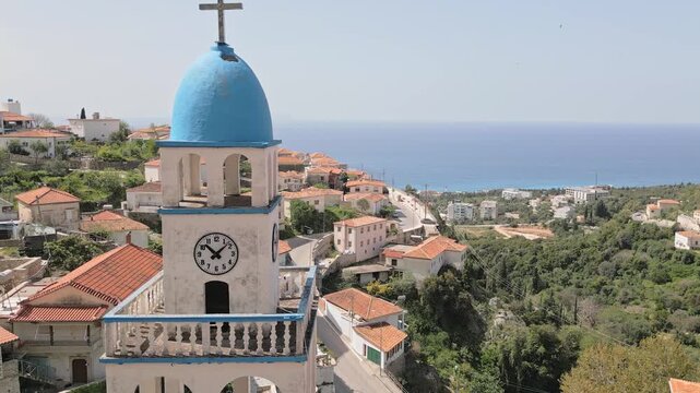 Aerial St. Spyridon Church in Dh&euml;rmi. White stone Orthodox chapel with blue domes overlooks Ionian Sea. Historic coastal architecture in Albanian Riviera, Albania