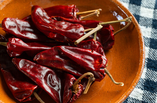 Macro shot of red dried guajillo chilies in handcrafted clay bowl