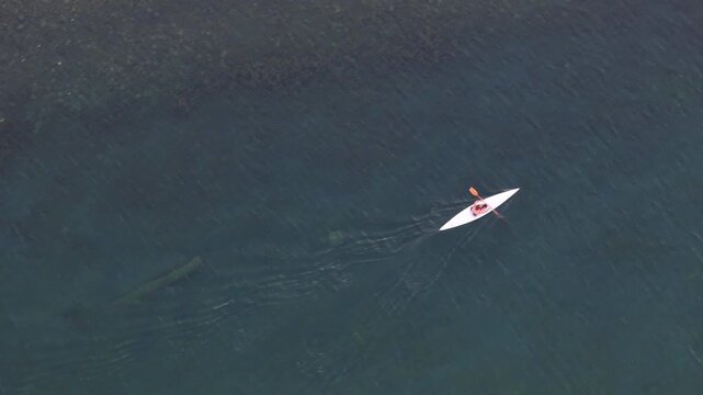 Kayaker gliding through clear waters, spotting a shadow beneath the surface on a sunny afternoon adventure