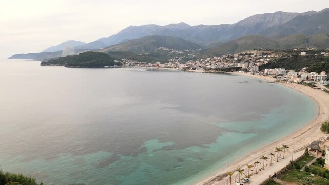Scenic aerial panning view gentle calm waves and pebbled shoreline at Himara Beach along the stunning Albanian Riviera. A perfect relaxing Mediterranean travel destination in EUROPE