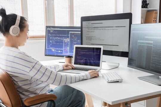 Female programmer with headphones working at desk in office