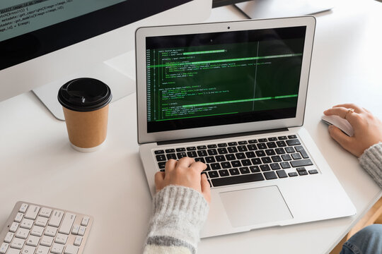 Female programmer's hands working with laptop at desk in office
