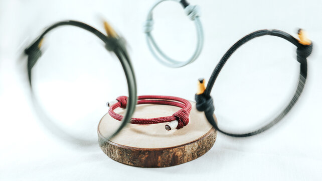 Maroon paracord bracelet on a wooden slice.