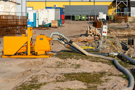 Industrial dewatering pump and hose system operating at construction site excavation for drainage