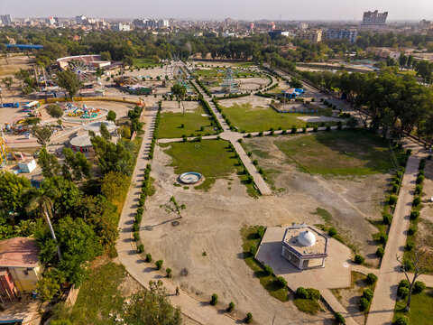 Aerial view of Rani Bagh park featuring green lawns, walking paths, and amusement rides under a clear sky in Hyderabad, Sindh, Pakistan.