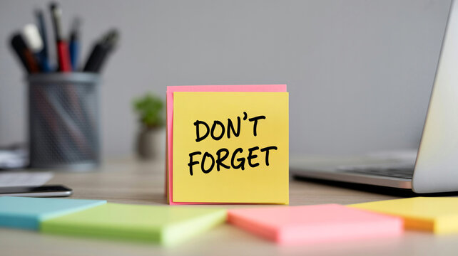 Yellow sticky note with dont forget text on office desk