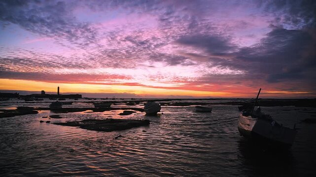 Spektakul&auml;rer Sonnenuntergang am Strand La Caleta in C&aacute;diz mit Fischerbooten und Leuchtturm Castillo San Sebastian