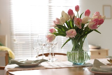 Naklejka premium Stylish table setting with beautiful tulips, dishware and glasses in dining room