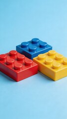 Naklejka premium A close-up of three colorful plastic building blocks on a light blue background, perfect for kids and children to play and learn