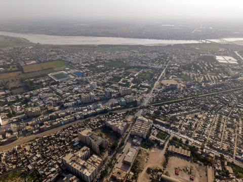Aerial view of the dense urban landscape featuring residential buildings, busy streets, and the Indus River in the background in Hyderabad, Sindh, Pakistan.