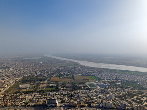 Aerial view of the urban landscape and the Indus River under a clear sky in Hyderabad, Sindh, Pakistan.
