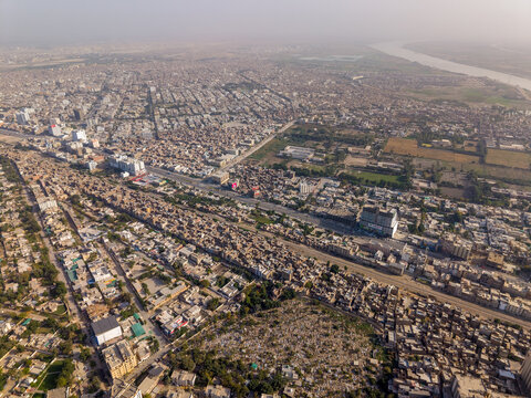 Aerial view of the dense urban landscape featuring a long straight road and the Indus River in the distance in Hyderabad, Sindh, Pakistan.