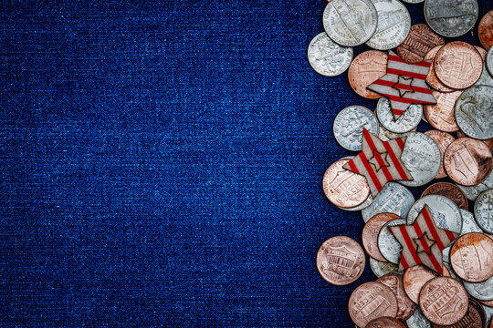 Many coins and red paper shapes are arranged on a blue fabric background with space for text or design