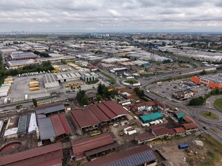 Fototapeta premium Industrial Landscape Overview: An expansive aerial perspective captures an industrial landscape dotted with warehouses, roads, and infrastructure under a sprawling sky. 
