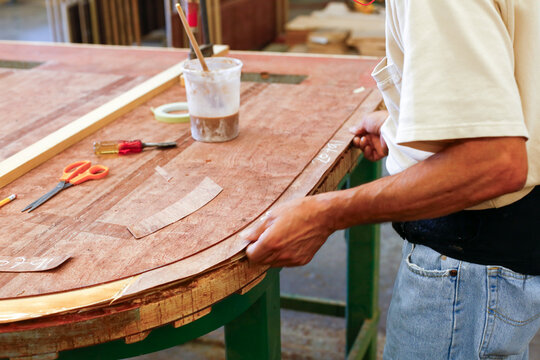 Craftsperson shaping wood for piano production