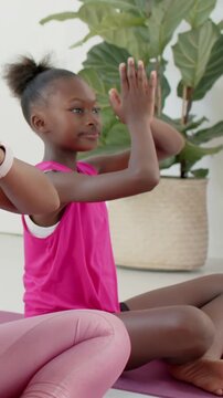 Vertical video: Following breath cue, mom-daughter meditating at home in tanks with pink mats