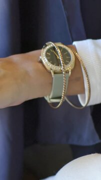 Vertical video: Turning her left wrist close, chains shifting on watch while fixing jewels in white