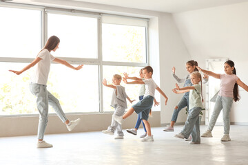 Fototapeta premium Group of little children with teacher dancing in studio