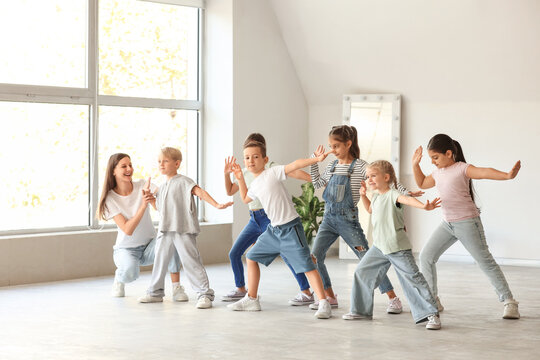 Group of little children with teacher dancing in studio