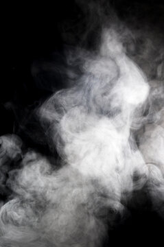 Wisps of white smoke swirling and dancing against a deep black background