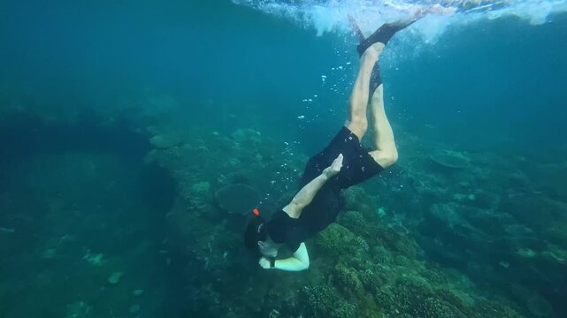 Freediver gliding above vibrant coral reef with yellow fins slow graceful descent across coral plates reveals reef topology, clear turquoise water, calm bubbles and peaceful, Amed,Bali