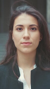 Woman dons mask calmly outdoors, Serene woman carefully places and removes surgical mask on office building steps