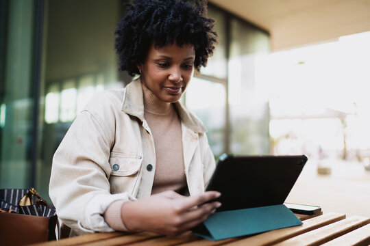 Black woman professional reviewing data on digital tablet, African American female entrepreneur working remotely, business technology, career growth, financial freedom, authentic representation.