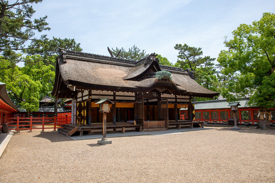 Traditionelles japanisches Shinto-Schreingeb&auml;ude mit Strohdach und roter Holzarchitektur in gr&uuml;ner Parklandschaft