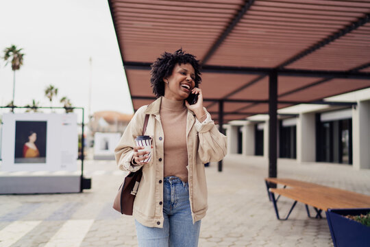 Smiling Black woman lying on bench using digital tablet with stylus, happy African American freelancer working outdoors, creative designer, digital nomad lifestyle, authentic representation.