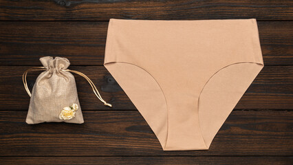 Beige High-Waist Underwear and Burlap Bag on Wooden Background for Fashion and Eco-Friendly Concepts