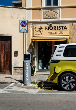 A lime green Volkswagen ID. Buzz electric van charging at an Enel Way station outside Fiorista Claudia Flor in Olbia, Sardinia, Italy.