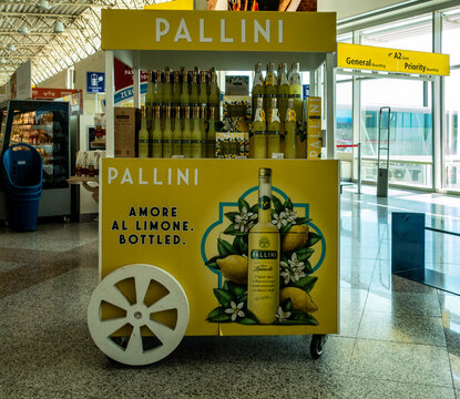 Pallini Limoncello display cart at Olbia Costa Smeralda Airport, Italy. The yellow cart features lemon graphics and bottles of Italian liqueur.