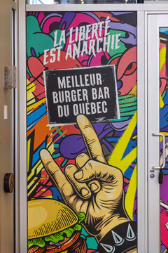 MONTREAL, CANADA, 24 December 2025 : Colorful wall art burger restaurant anarchy theme Quebec burger bar graffiti hand gesture spiked bracelet vibrant design