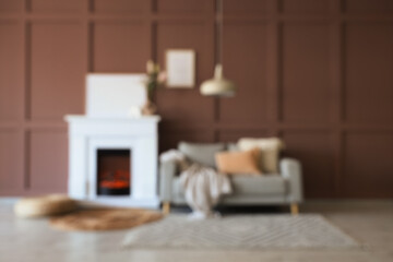 Obraz premium Blurred view of cozy living room with grey sofa, wicker pouf and stylish fireplace