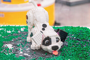 Naklejka premium 14 January 2026, Dubai, UAE: Dalmatian puppy statue made from Lego bricks, standing on a surface covered with miniature green toy elements