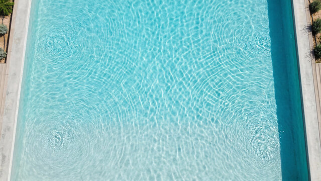 Clear turquoise swimming pool water surface with sunlight ripples, 16:9