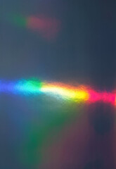 Abstract image of a vivid rainbow light spectrum reflected on a dark surface, featuring smooth...