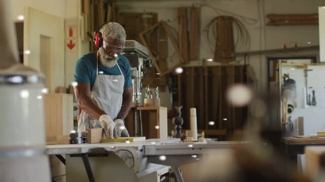 Woodworker measuring board for precise cut and guiding board across saw in woodshop, bokeh floating