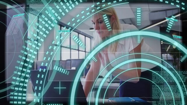 Woman leaning, assessing laptop, adjusting hair and typing while teal HUD overlaying her in office