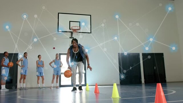 Trainer starting basketball dribble showing moves past cones while network overlay growing to coach