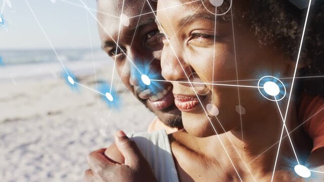 Man embracing woman on sunny beach, overlay fading in mapping network nodes across faces for tech