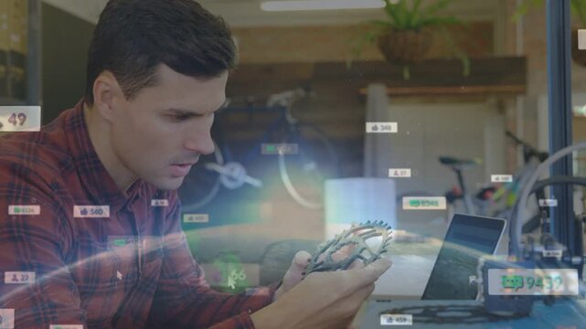 Male maker inspecting gear in maker lab, glancing at laptop phone, starting AR overlay checking fit