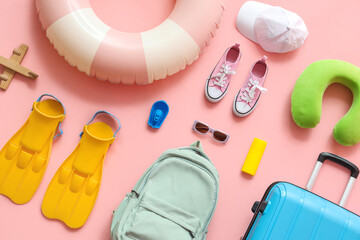 Summer composition with suitcase, inflatable ring, travel pillow, flippers and backpack on pink background © Pixel-Shot