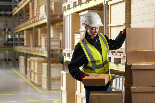 Warehouse logistics, Order fulfillment. Female worker sorts cardboard boxes on storage rack in distribution warehouse, handling packaged goods and inventory.