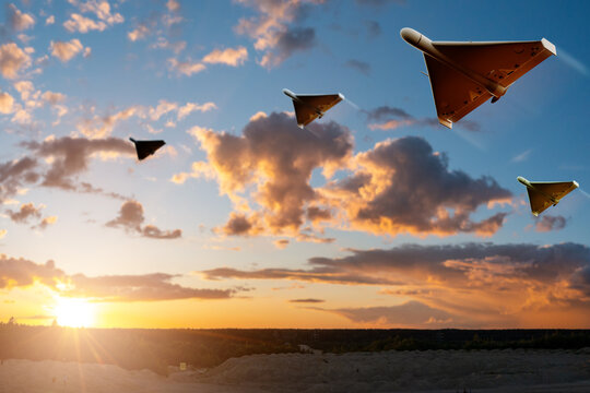 Unmanned combat aerial vehicles fly in formation at sunset over a rugged landscape, showcasing advanced military drone technology, surveillance capability, and autonomous aerial operations