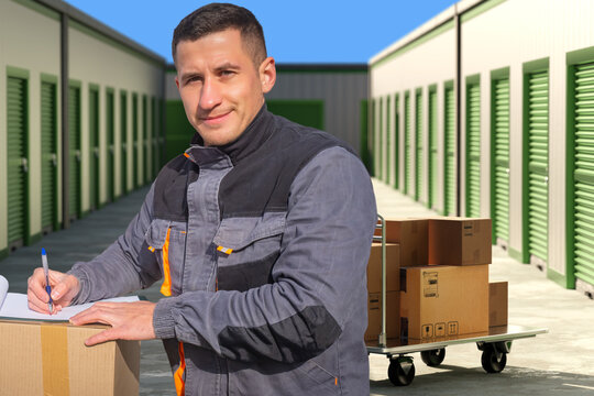 Self storage operations, Parcel handling. Worker records package inventory and manages box delivery beside storage units and transport cart.