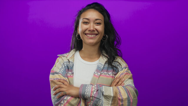 Woman smiling with arms crossed and visible hands in studio against purple backdrop; confidence empowerment warmth.
