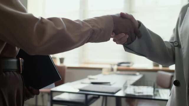 Low angle close up shot of two unrecognizable woman finishing business meeting by shaking hands after making deal in office
