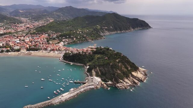 Aerial view of the Baia del Silenzio peninsula with boats anchored in turquoise waters and colorful houses along the coast in Sestri Levante, Liguria, Italy.